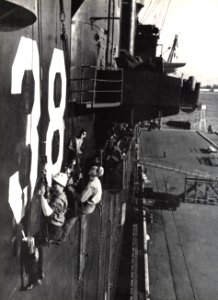 Sailors paint the hull number of USS Shangri-La (CV-38) on its starboard side, circa in December 1945