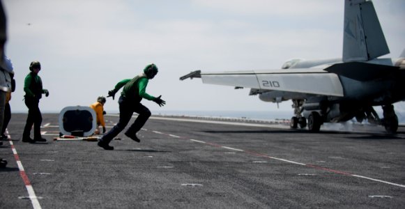 Sailors retrieves hold-back bar during flight operations at sea. (8721188074)
