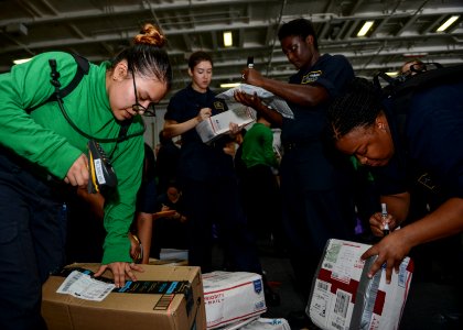 Sailors sort mail in the hangar bay of the aircraft carrier USS Nimitz (CVN 68) during exercise Malabar 2017