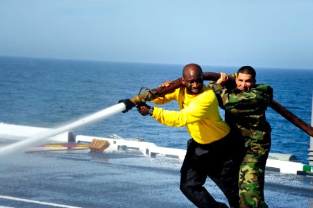 Sailors use a firehose during a flight deck washdown. (8448065820)