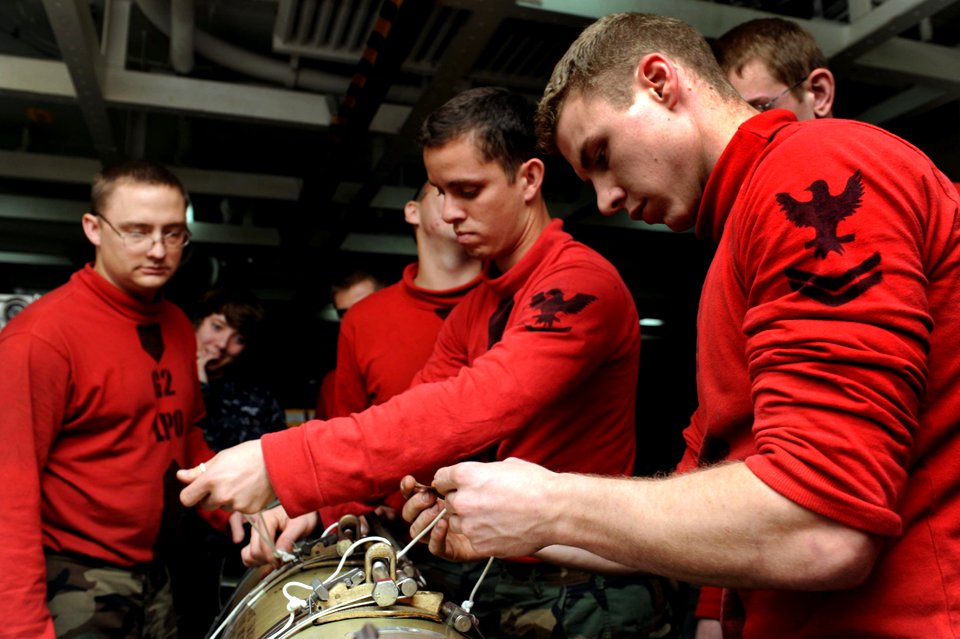 Sailors remove bands from a torpedo at sea. (8427155816)