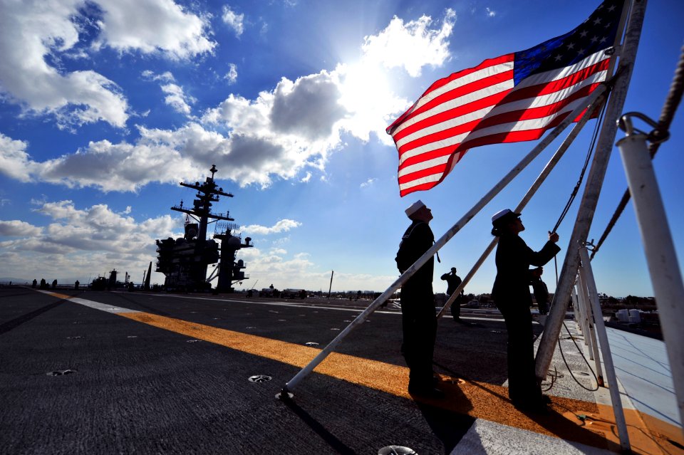 Sailors bring down the American flag as USS Carl Vinson gets underway. (8470064363)