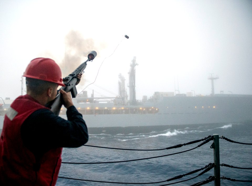 Sailor firing shot line from USS Lake Champlain (CG-57) to USNS Yukon (T-AO-202) during underway replenishment US Navy 161108-N-FT178-008