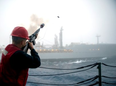 Sailor firing shot line from USS Lake Champlain (CG-57) to USNS Yukon (T-AO-202) during underway replenishment US Navy 161108-N-FT178-008