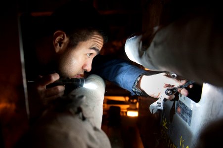 Sailor works on a refrigerator compressor in a cold storeroom. (24317170217)