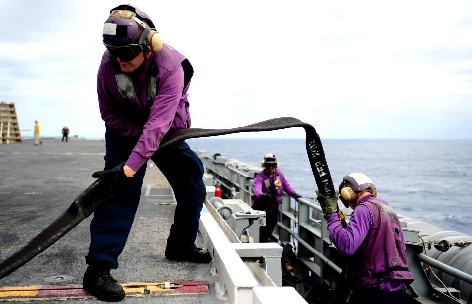 Sailors handle a fuel hose at sea. (8448062508)
