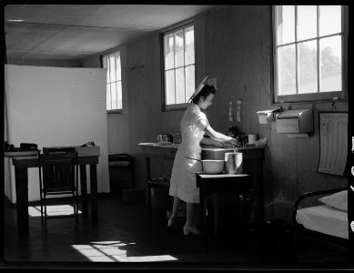 San Bruno, California. An evacuee nurse of Japanese ancestry tidying up after a busy morning in the . . . - NARA - 537935 photo