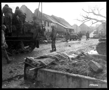 SC 197206 - American soldiers move up to the front, past the form of a fallen Yank on a litter, near Bastendorf, Germany. November 26, 1944