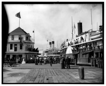 Scene at a dock with side-wheeler ferries and people on pier and on ships LCCN2006683675
