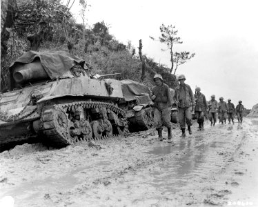 SC 208600 - Soldiers of the 77th Inf. Div. walk past mud-clogged tanks parked by the side of the road on Okinawa. 26 May, 1945