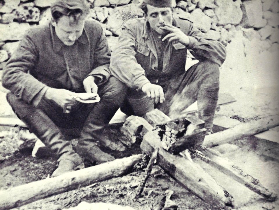 Saniteteni referent 14. divizije Stane Pirc in njegov pomočnik Albin Polk Fajfa ob ognju v taboru 14. divizije na Starih ogencah nad Leskovo dolinu v začetku novembra 1943