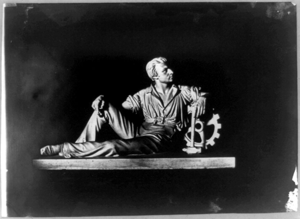 Sculpture of man with a hammer leaning on a gear LCCN2002718507