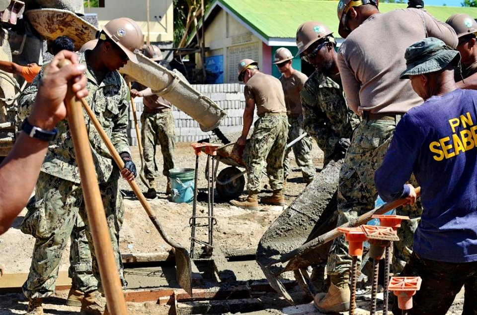 Seabees from Naval Mobile Construction Battalion (NMCB) 5 and Republic of Philippines Navy Seabees work together to finish placing concrete