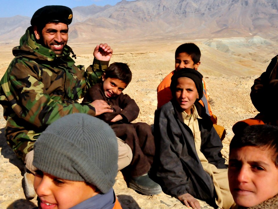 An Afghan National Army soldier providing security for a live fire range sits with children (4335158870)