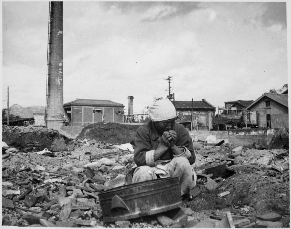 An aged Korean woman pauses in her search for salvageable materials among the ruins of Seoul, Korea. - NARA - 531387