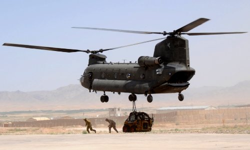 An Australian Army CH-47 Chinook Helicopter lifts a front loader off the flight line at Special Operations Task Force Southeast's FOB Camp Ripley