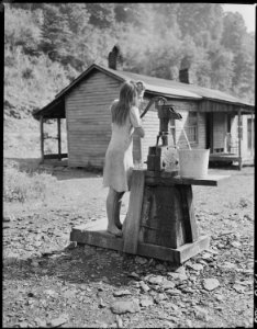 Daughter of Ceph Holland getting water. This one pump is the only approved water source in the camp. There is a... - NARA - 541145