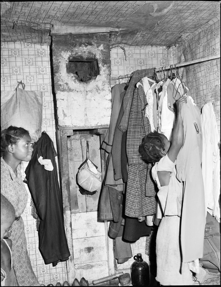 Daughter of Lawson Mayo hanging up clothing. The house was in bad repair when they moved in, nothing has been... - NARA - 540967