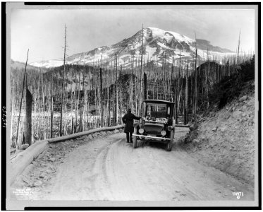 A Detroit Electric automobile stopped on road by burnt-over land, with snow-covered mountain in background, Washington LCCN92511952