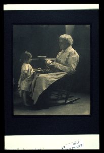 Elderly woman in a rocking chair peeling apple with young girl standing in front of her LCCN2004676230 photo