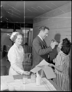 Granada Relocation Center, Amache, Colorado. Doctor Gerald A. Duffy, resident physician, examining . . . - NARA - 538744 photo