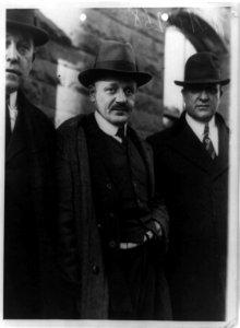 Hans Schwartz, three-quarter length portrait, standing, facing slightly right, with two detectives on way to court, New Jersey LCCN91787242
