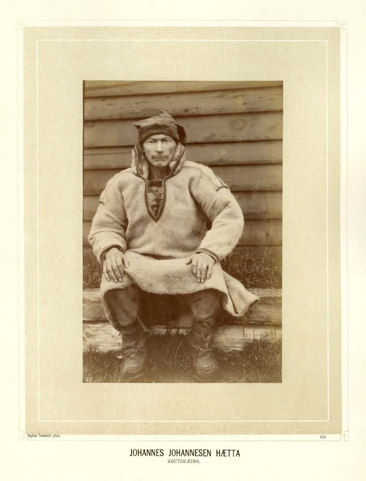Johannes Johannesen Hætta sitter på en trebenk utenfor bygning - Norsk folkemuseum - NF.15006-070