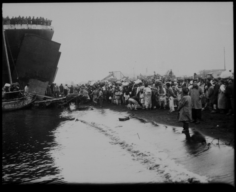 Korean natives prepare to board a tank landing ship during the evacuation of Hungnam, while other refugees unload... - NARA - 520781