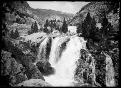 La cascada del Bozuelo amb alguns arbres i muntanyes al fons
