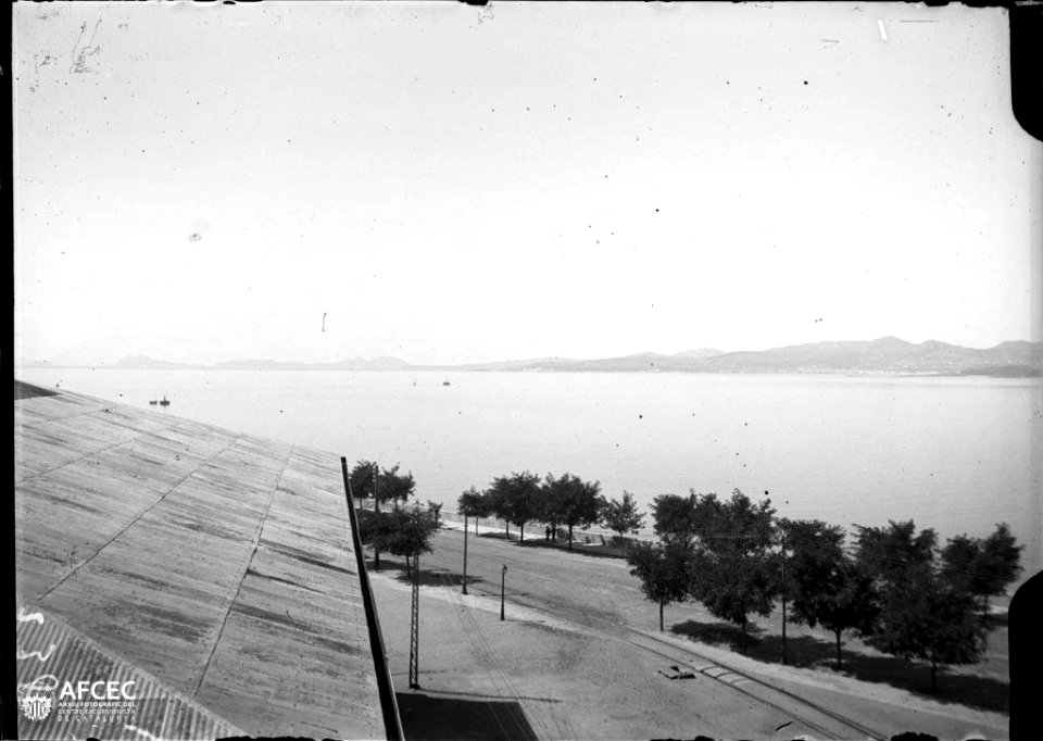 La ria de Vigo i a la riba un edifici i un passeig amb arbres
