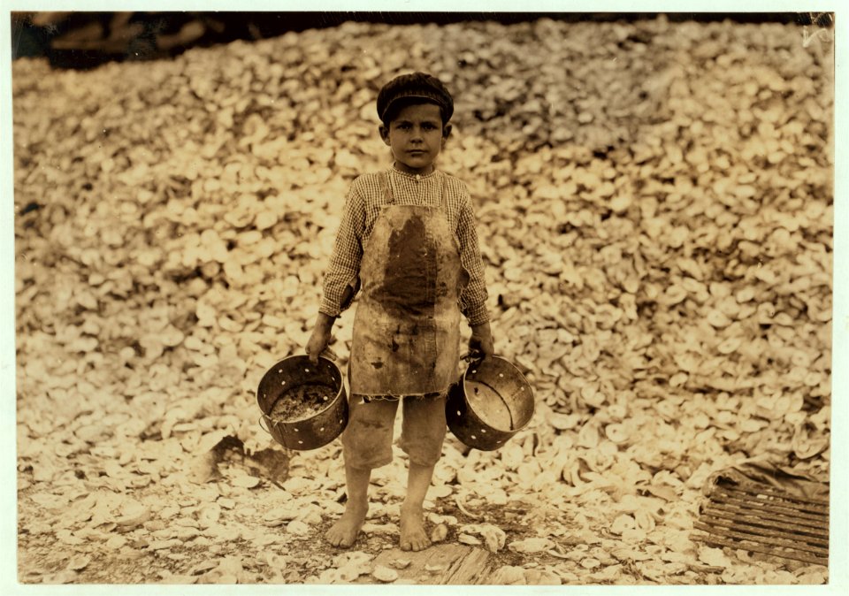Manuel, the young shrimp-picker, five years old, and a mountain of child-labor oyster shells behind him. He worked last year. Understands not a word of English. Dunbar, Lopez, Dukate LOC cph.3a01213