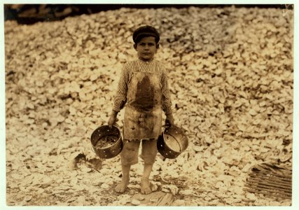 Manuel, the young shrimp-picker, five years old, and a mountain of child-labor oyster shells behind him. He worked last year. Understands not a word of English. Dunbar, Lopez, Dukate LOC cph.3a01213