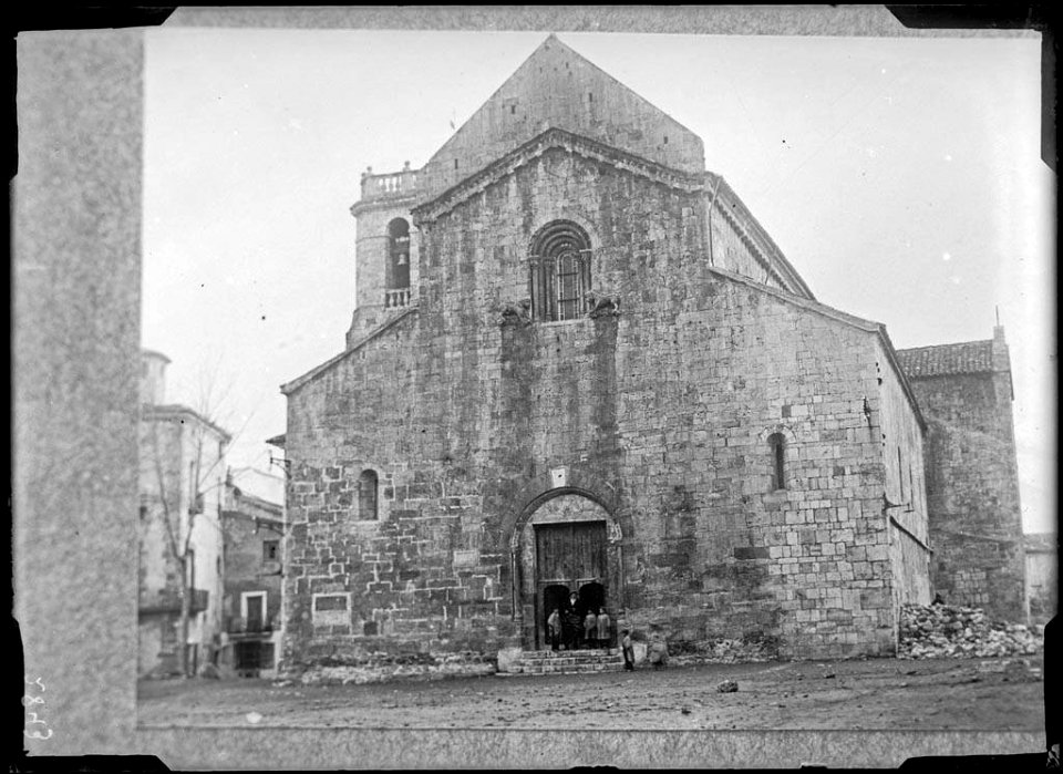 Plaça i monestir de Sant Pere de Besalú amb un grup de persones al portal (AFCEC VINTRO D 2843)