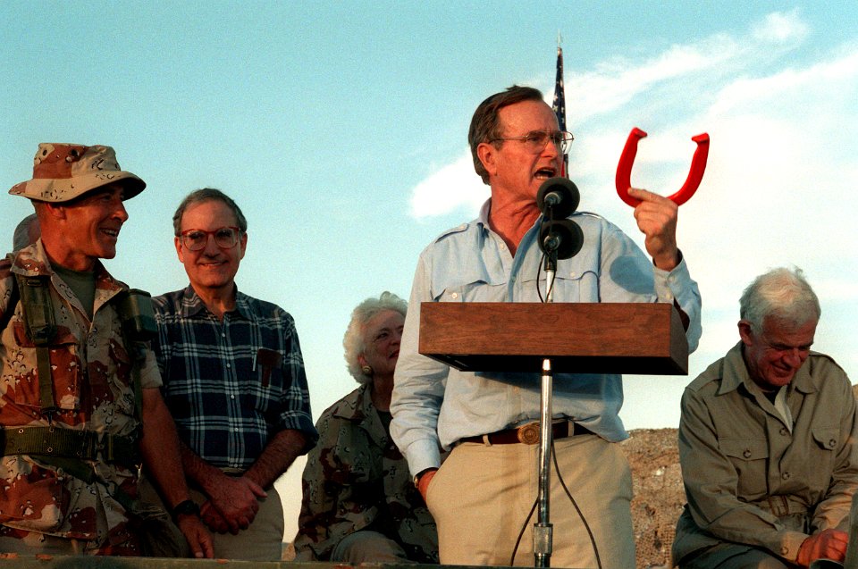 President George H. W. Bush holds up a horseshoe as he addresses the Marines and Seabees at a desert encampment