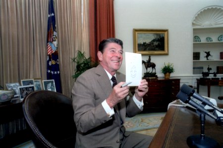 President Ronald Reagan holding up one of his doodles to the press