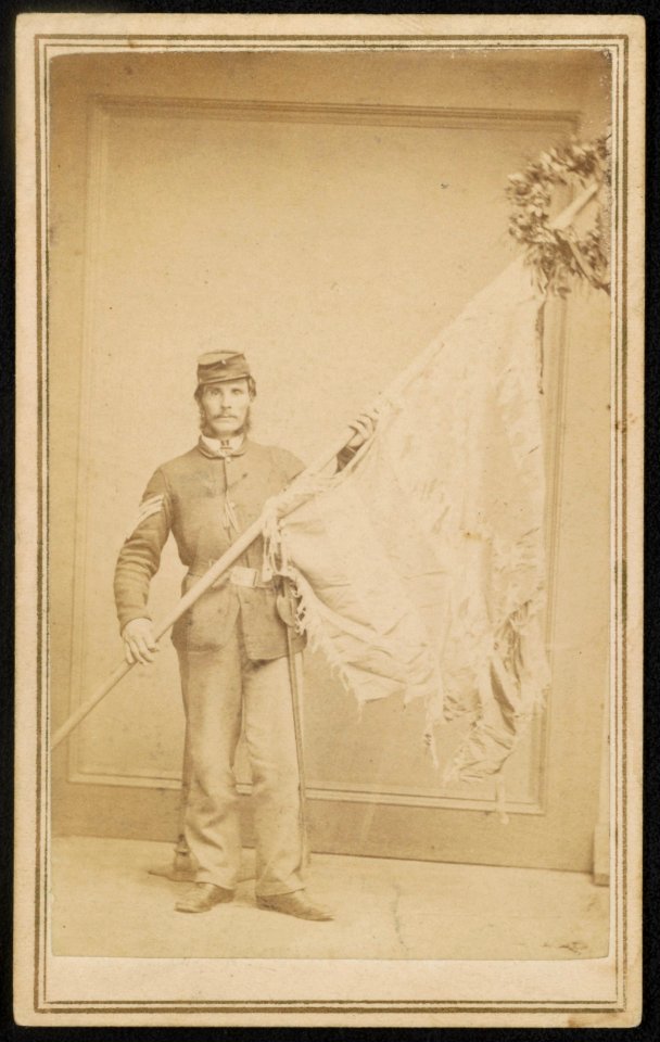 Second Lieutenant John C. Nutting of Co. I, 4th New Hampshire Infantry Regiment in uniform displaying tattered regimental flag) - Kimball & Sons, State Block, Cor Main and School Sts., LCCN2016651692