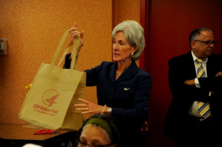 Secretary Sebelius shows a reusable STOP Medicare Fraud bag while touting HHS and DOJ's joint Health Care Fraud Prevention Summits