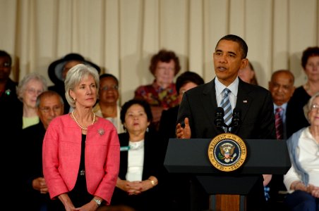 Secretary Sebelius stands by President Obama as he speaks to Seniors at the Holiday Park Multipurpose Senior Center in Wheaton, MD