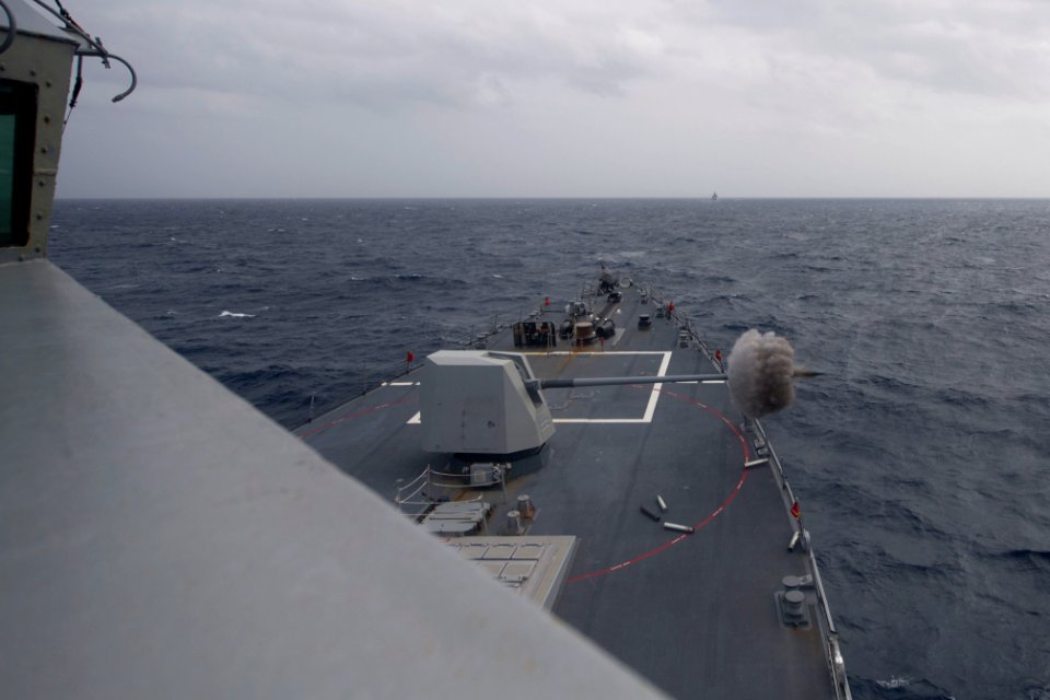 The Arleigh Burke-class guided missile destroyer USS Shoup (DDG 86) fires its Mark 45 5-inch gun during a live-fire exercise during Malabar 2017