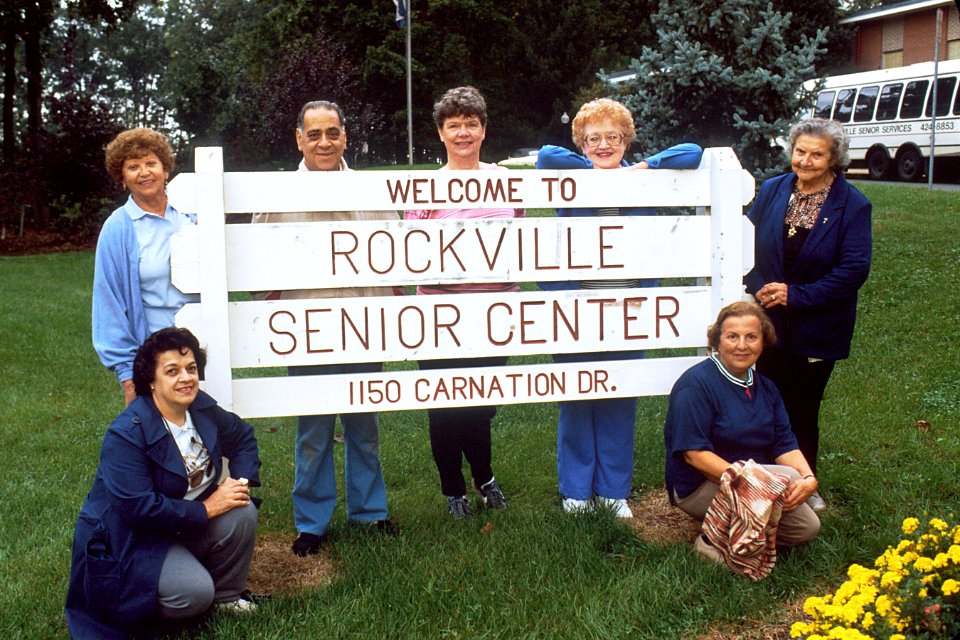 Senior citizens gathered around sign