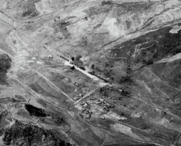 Shells from USS Saint Paul (CA-73) hit a railway station in Korea, circa in late 1950