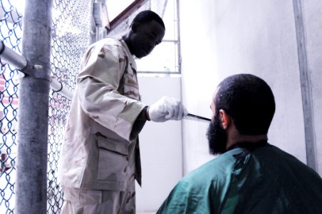 Ship’s Serviceman 3rd Class Darold Johnsonbrown combs a detainee’s beard in Camp VI DVIDS367055