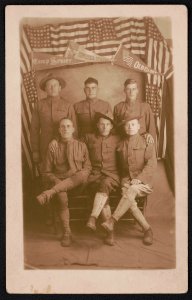 Six unidentified soldiers in front of American flags and pennants for Camp Sevier, United States, and Old Glory LCCN2018645957