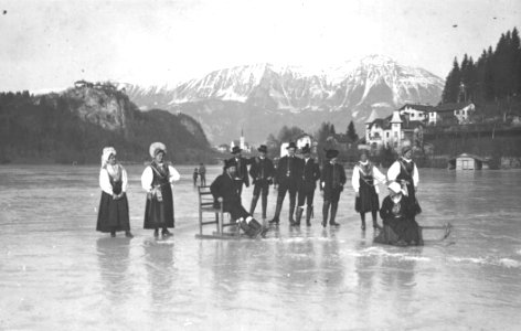 Skupina ljudi v gorenjski narodni noši na drsalkah, pozira na zamrznjenem Blejskem jezeru 1910-25