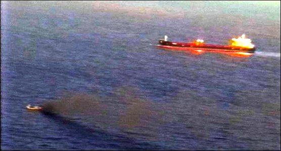 Smoke rises from the Taiwanese fishing vessel Shin Maan Chun, lower left, while the Marshallese-flagged bulk carrier Semirio responds to the boat's call for 120421-N-ZZ999-001