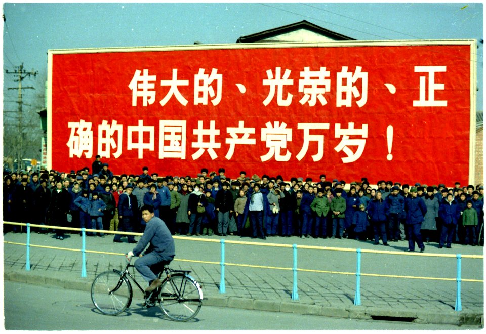 Spectators in front of a large sign on Nixon's motorcade route in China. - NARA - 194413