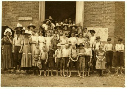 Spinning room Overseer and his flock. He said, 'Every one of 'em works or helps.' I saw them all working in the morning and when the whistle blew at noon they all went in to work. See photos LOC nclc.02087
