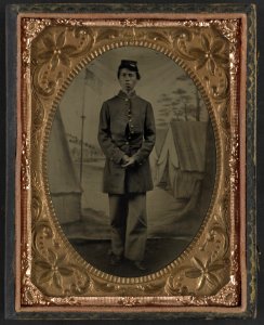 Standing soldier, frock coat, kepi, painted background, dirt floor, done by traveling camp photographer LCCN2002719394