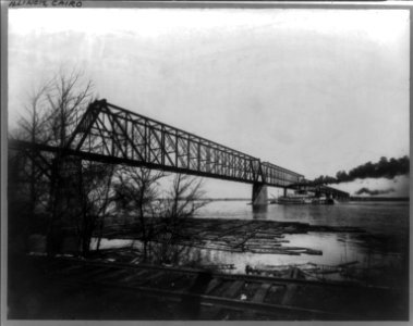 Stern-wheel riverboat passing under Illinois Central Railroad bridge over Ohio River, Cairo, Illinois, with logs lashed together at river's edge LCCN89711647