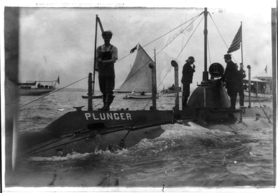 Submarine Plunger partially submerged, with four members of crew standing on top, at close range, Oyster Bay; yachts and sailboat in background LCCN97504615